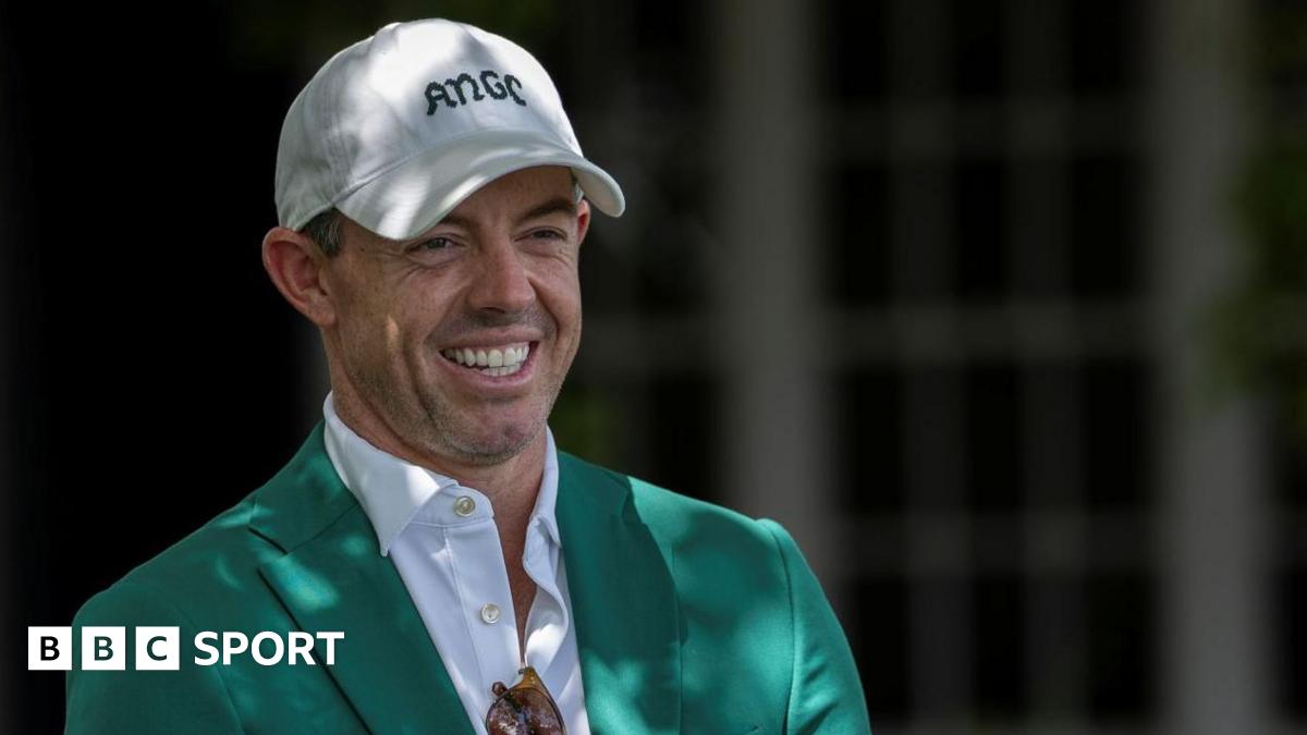 Rory McIlroy smiles as he talks to Augusta officials on his return to the Masters